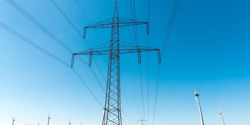 Strommast und Stromleitungen vor blauem Himmel