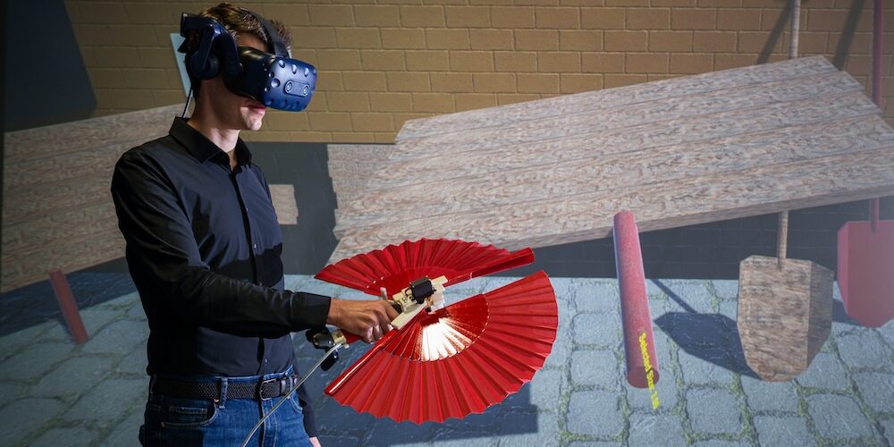 Mann mit VR-Brille und einem fächerartigen Controller in der Hand führt einige Tests in der virtuellen Realität durch.