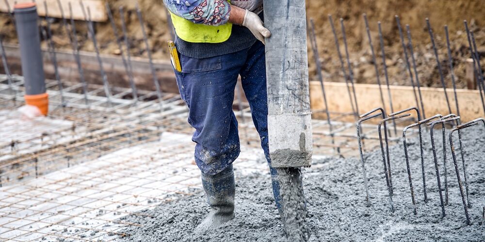 Mensch arbeitet auf dem Bau und gießt Beton auf eine Etage