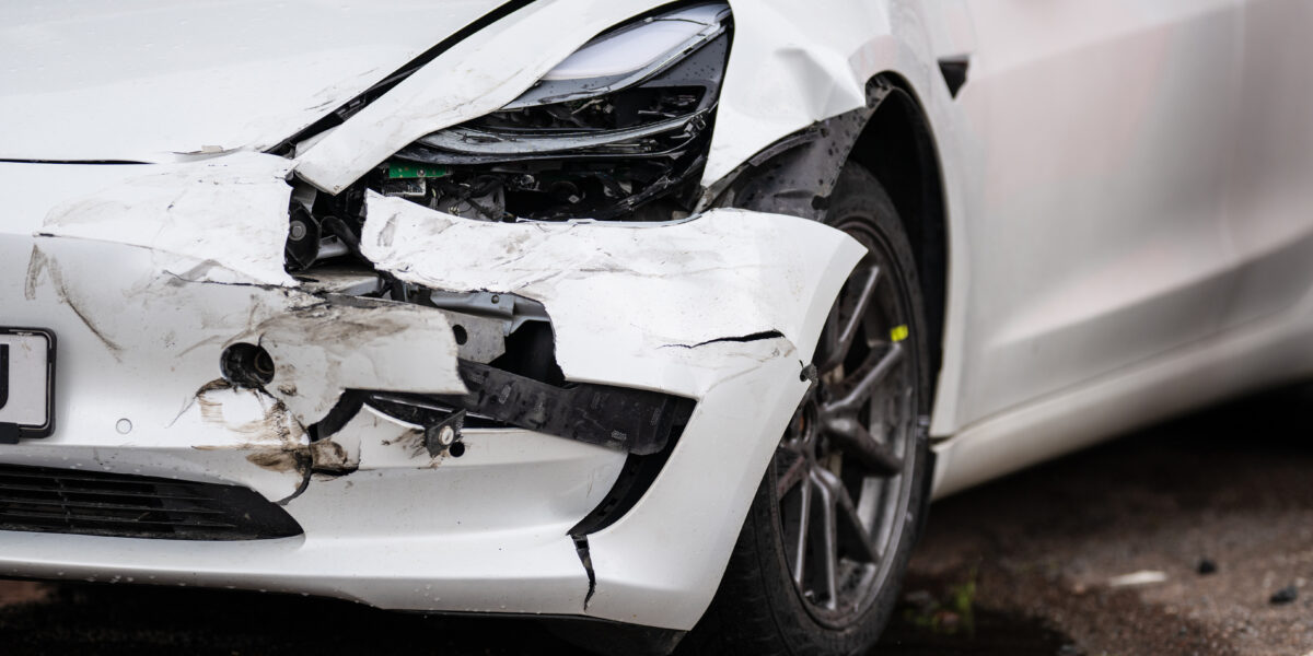 Crashed white electric car waiting for repair.