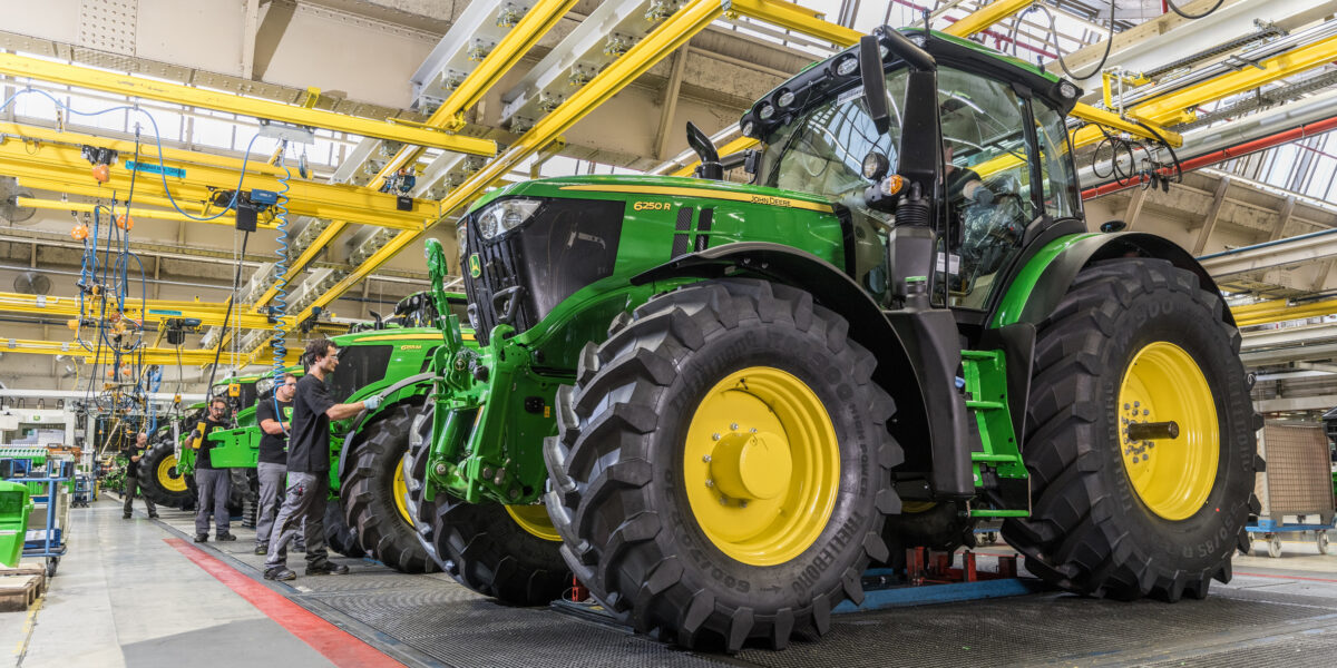 Mitarbeiter im John-Deere-Werk montieren im Bild Traktoren der Serie 6250R. Seit Kurzem werden sie von einer hochmodernen Lösung zur automatisierten Qualitätssicherung unterstützt. Foto: John Deere