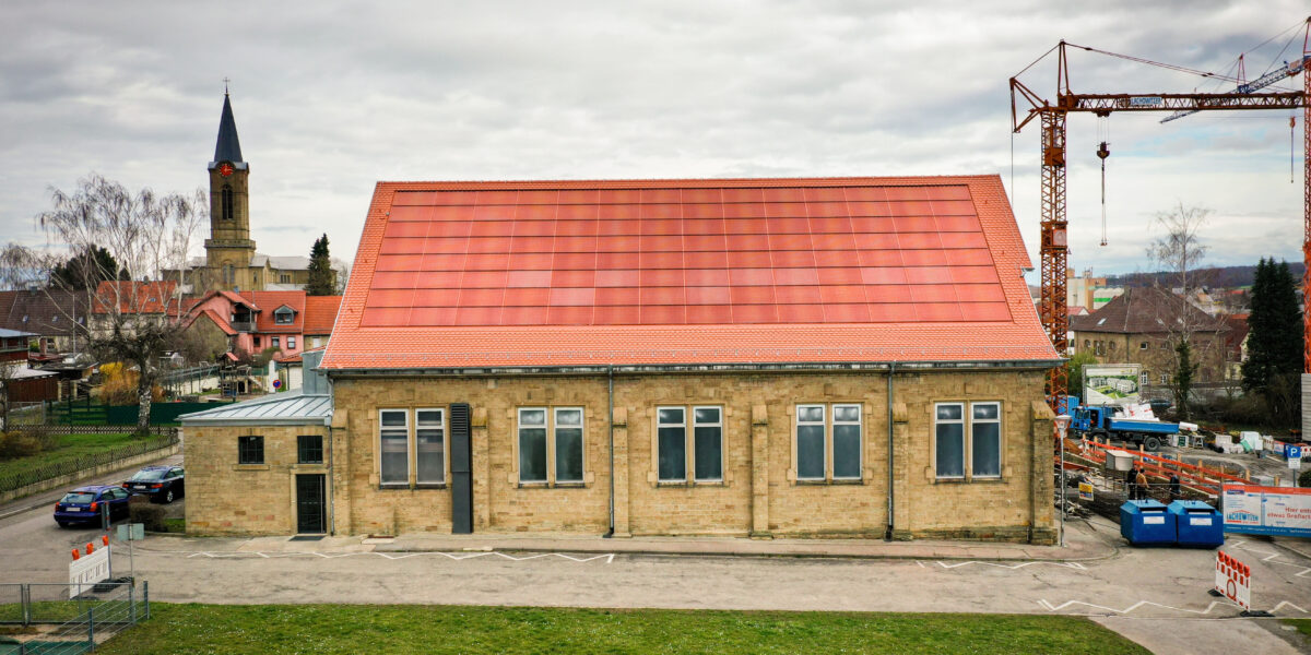 historische Turnhalle mit ziegelrot gefärbten MorphoColor®-Solarmodulen