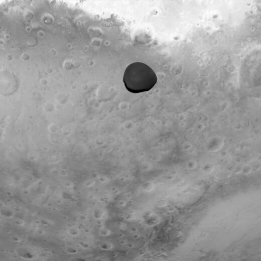 Der Marsmond Deimos erscheint dunkel, eingerahmt von dem helleren Planeten Mars im Hintergrund. Dieses monochromatische Bild aus dem Bereich des sichtbaren Lichtspektrums, aufgenommen von der Asteroid Framing Camera (AFC), wurde von der ESA-Raumsonde Hera während ihres Vorbeiflugs mit Nutzung der Schwerkraft am 12. März 2025 aufgenommen